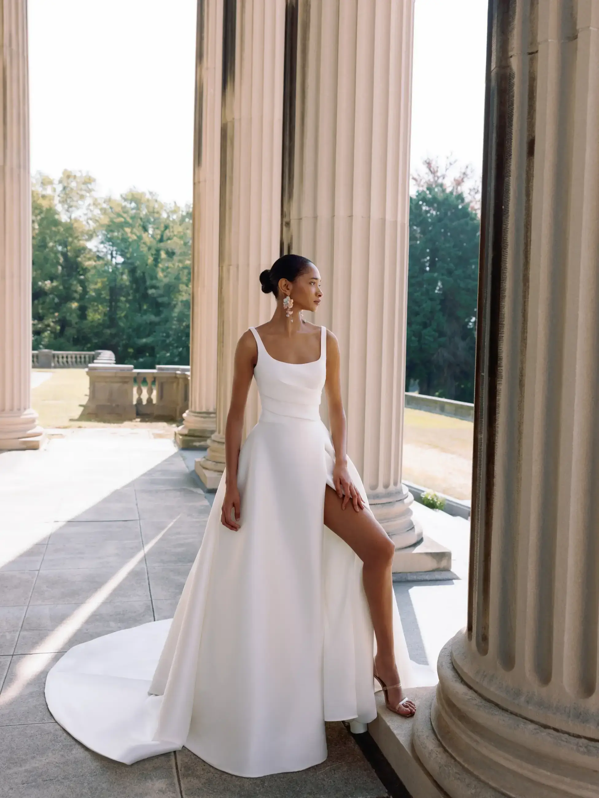Model is wearing a minimalist mikado wedding dress with a high slit and scoop neckline by sarah nouri