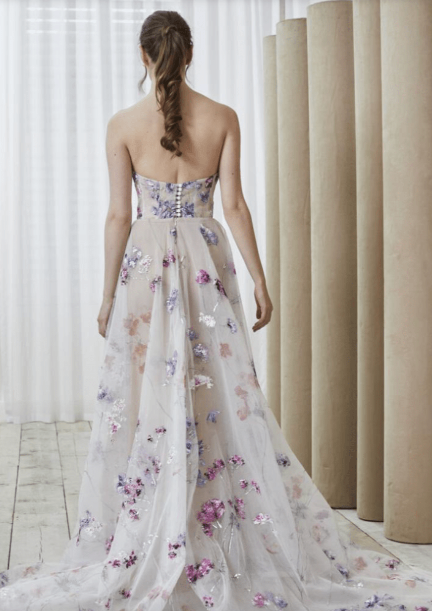 Model is wearing a hand painted wedding dress with a strapless, structured bodice 