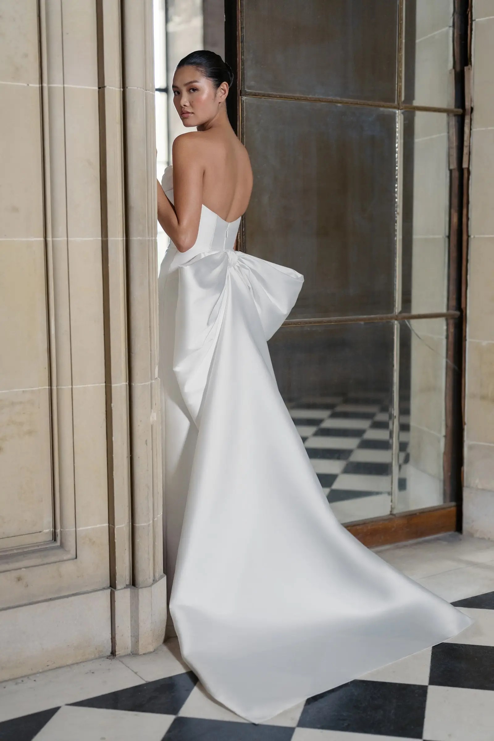 Model is wearing a mikado column bridal gown with a tailored bow on the back from anne barge couture