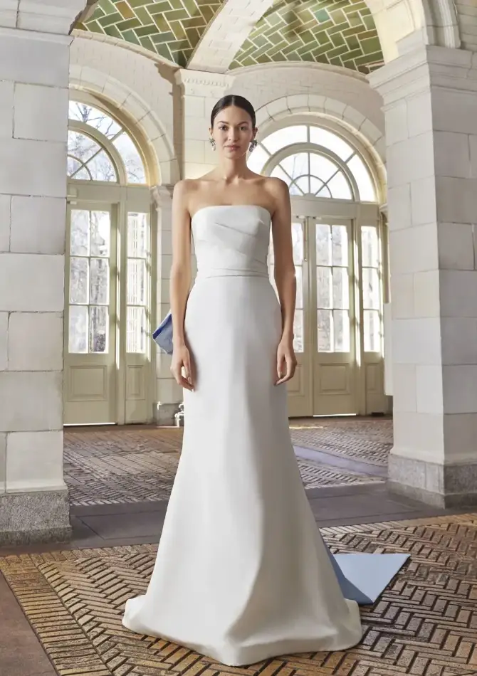 Model is wearing a silk slim flare wedding dress with a blue oversized bow in the back