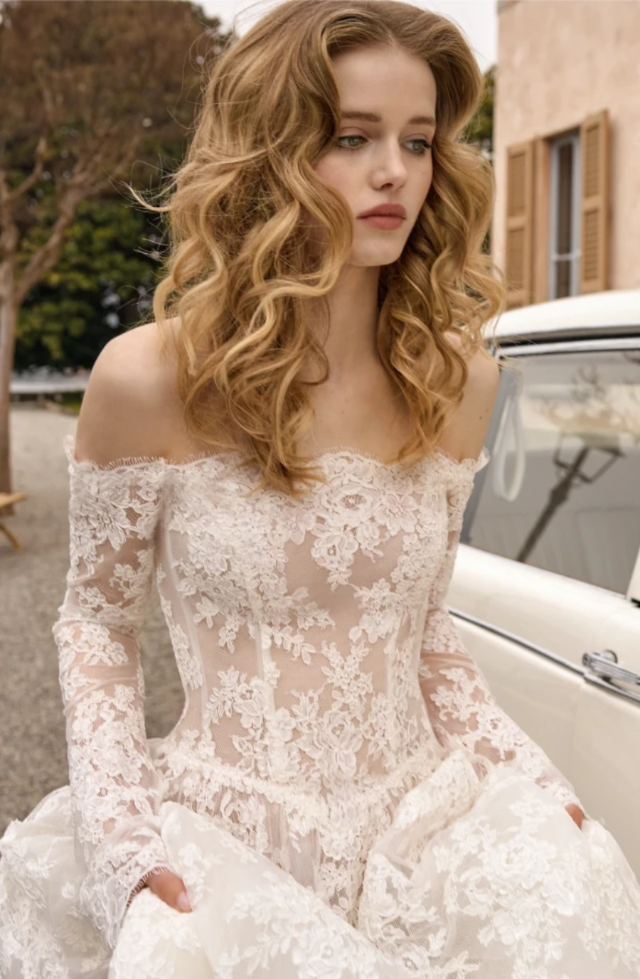 model is wearing an off the shoulder long sleeve lace bridal gown