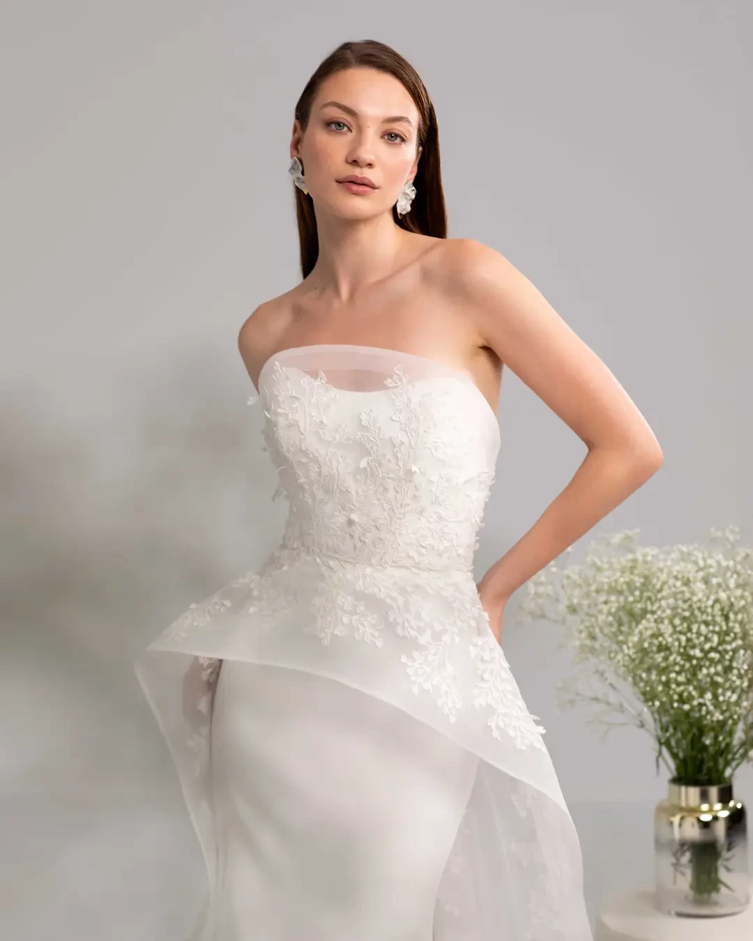 model is wearing a strapless peplum wedding gown