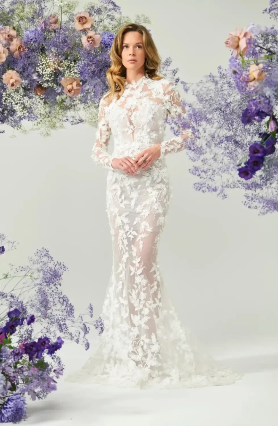 model is wearing a high neckline long sleeve allover lace sheath bridal gown