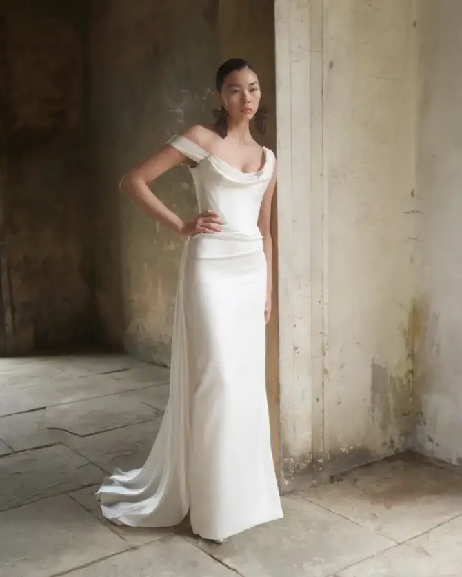 model is wearing an off the shoulder sheath wedding dress