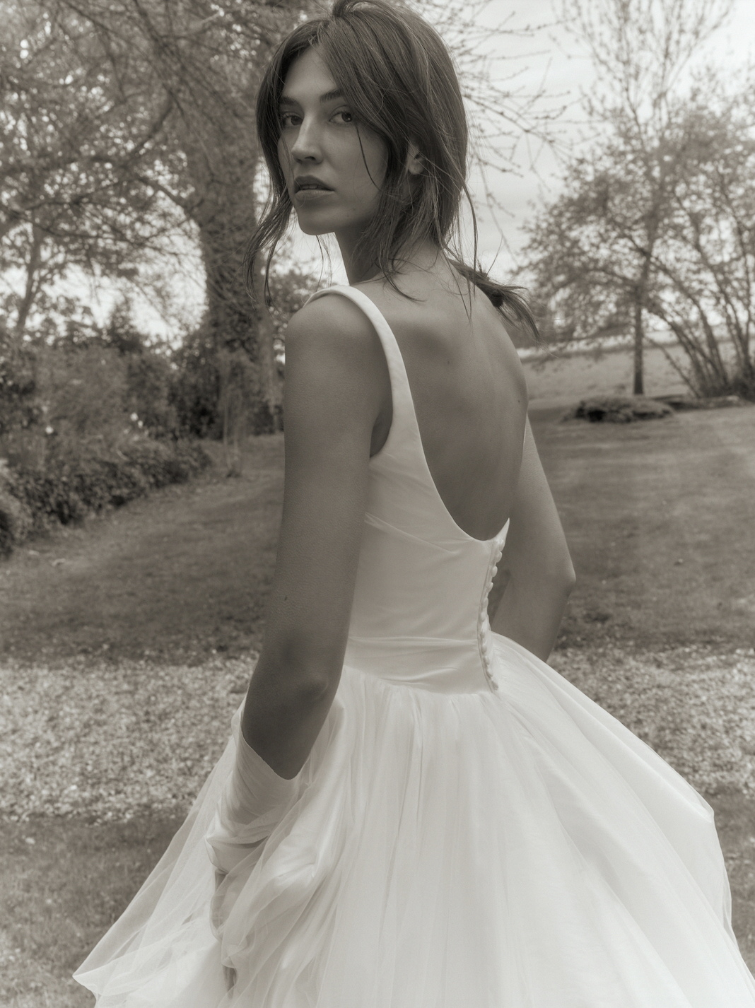 model is wearing an open back dana harel wedding gown