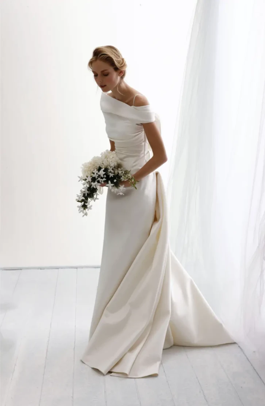 model is wearing an off the shoulder fit and flare wedding dress