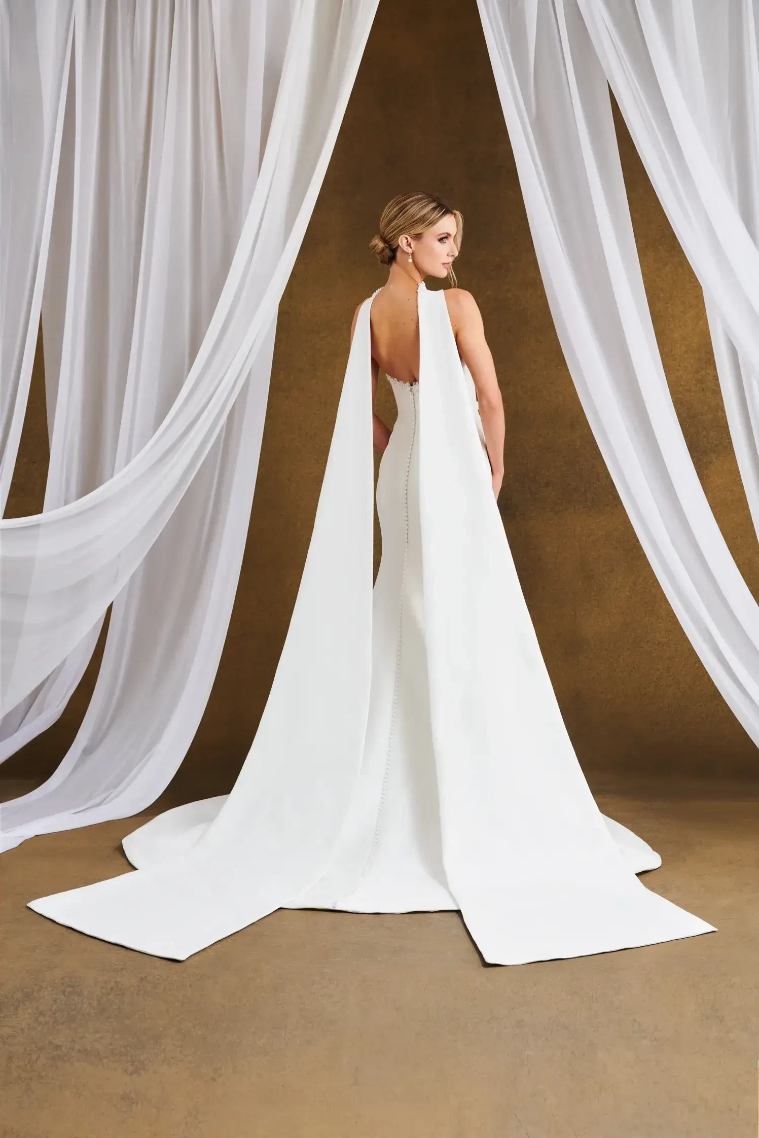 Model is wearing a Mikado fit-and-flare gown with a pearl and bead-trimmed neckline, structured bodice, and seam detailing.
